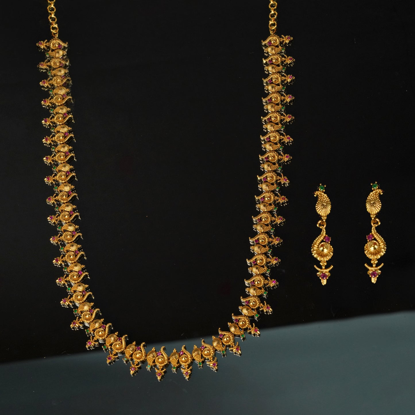 Gold necklace with intricate design and matching earrings.