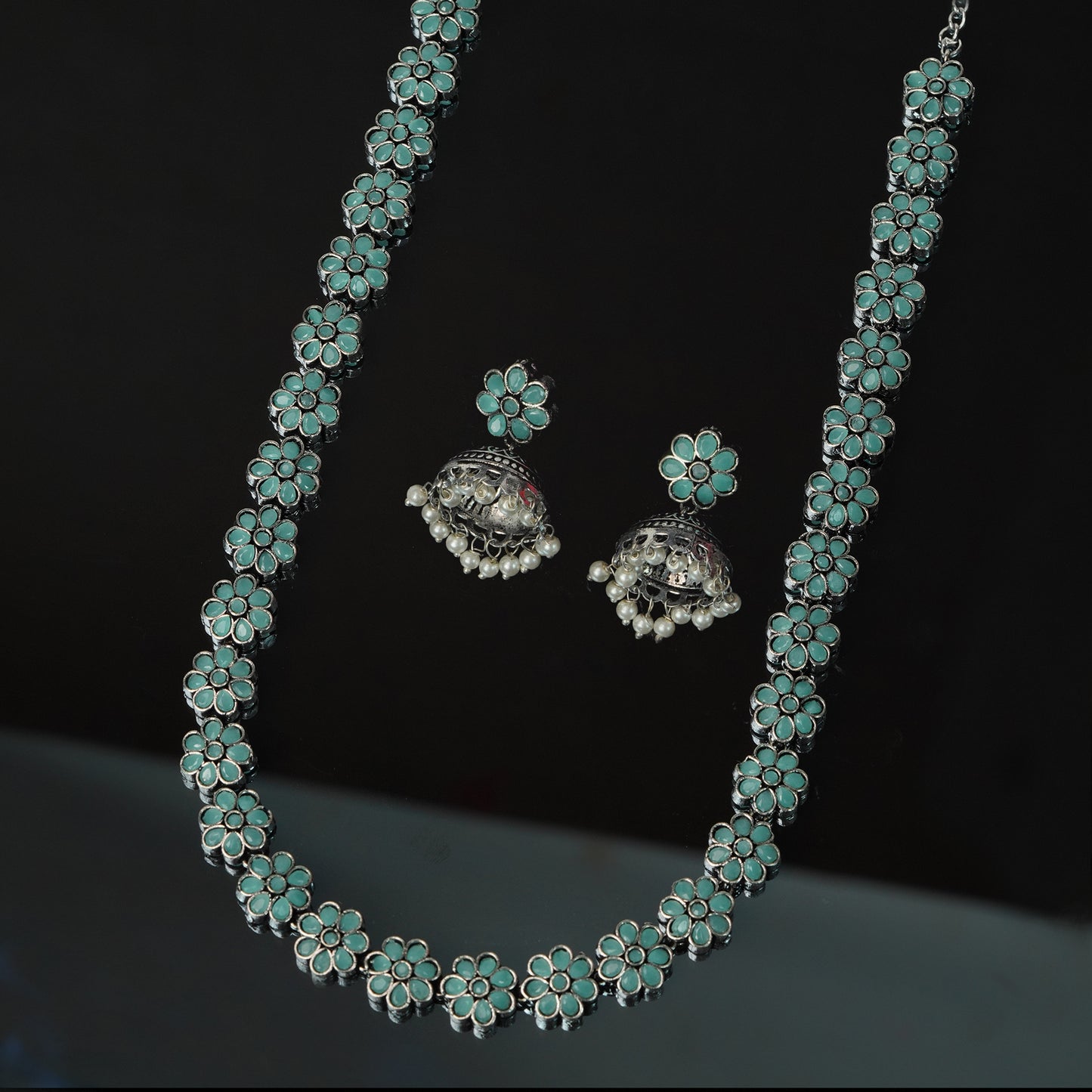 A silver necklace and matching earrings with turquoise flower designs.