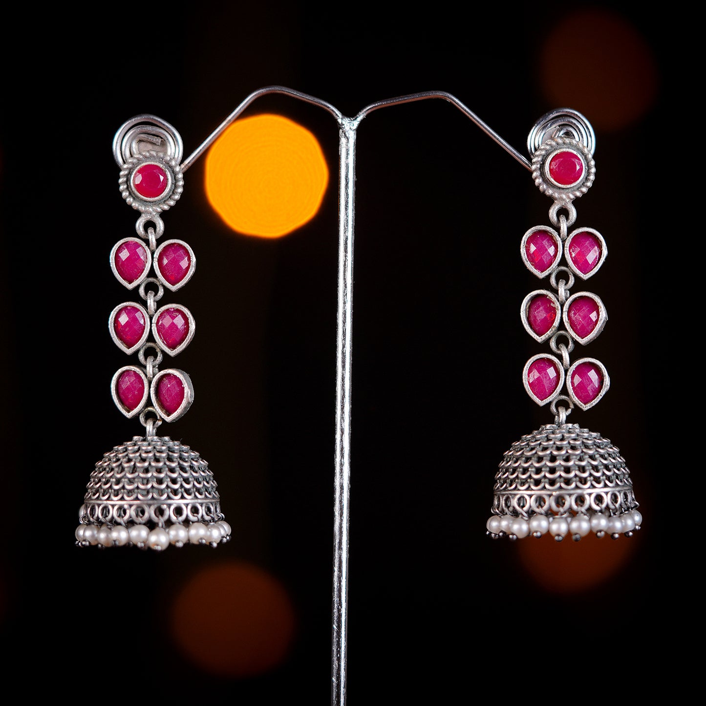 Silver jhumka earrings with pink gemstone accents.