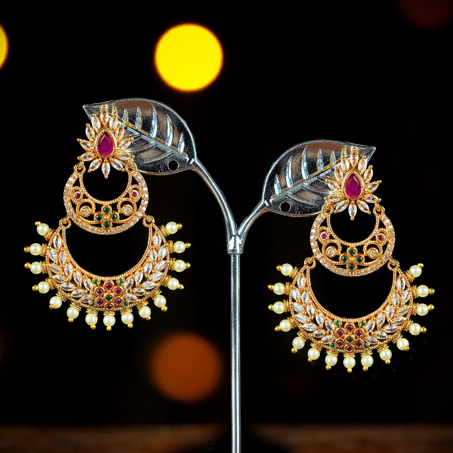 Gold and ruby chandelier earrings with intricate design and pearl accents.