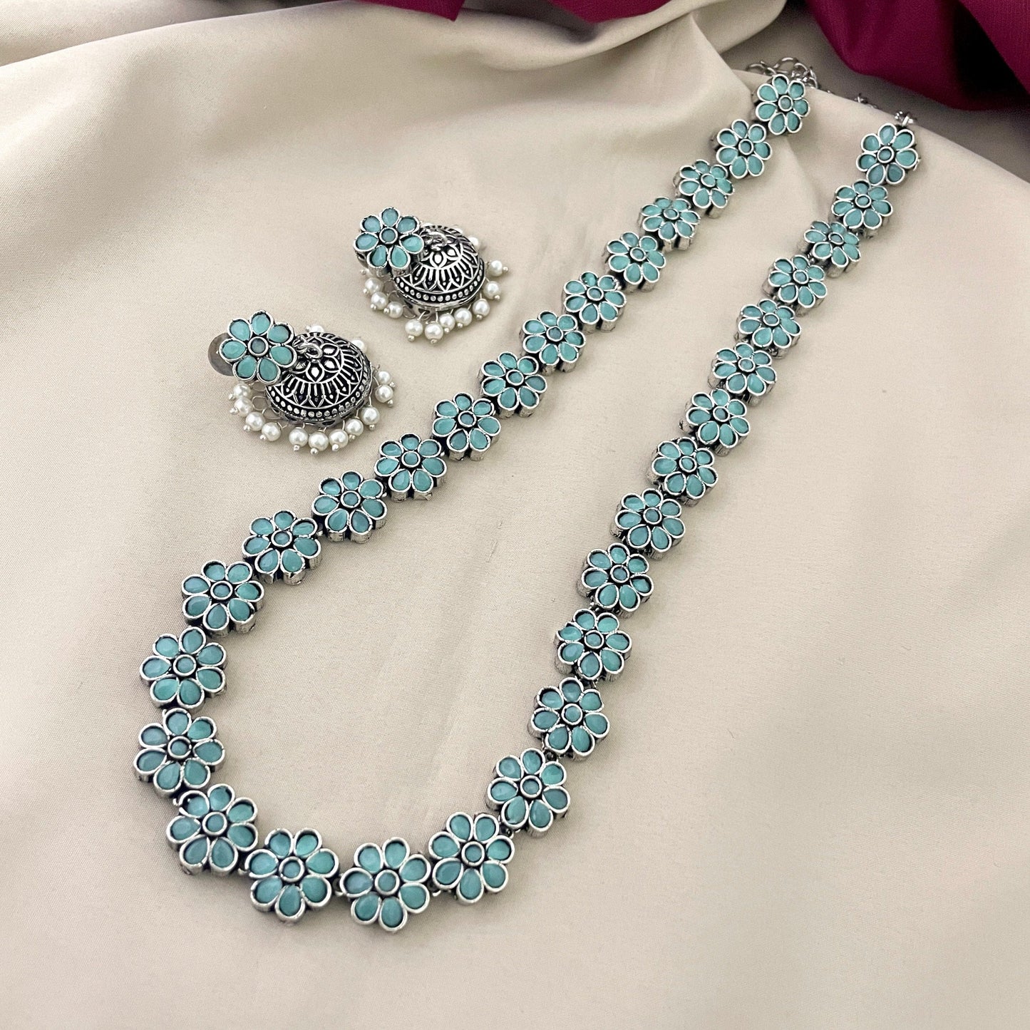 A jewelry set featuring a necklace and earrings with turquoise flower designs and silver accents.