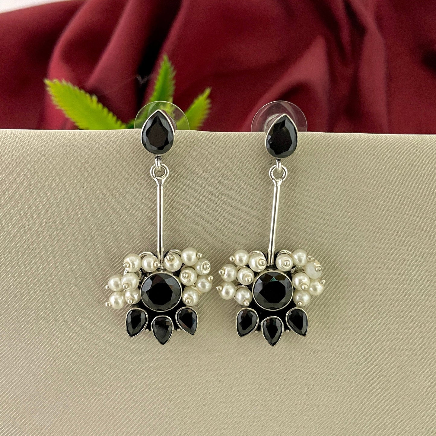 Silver earrings with black teardrop-shaped stones and small white pearls.