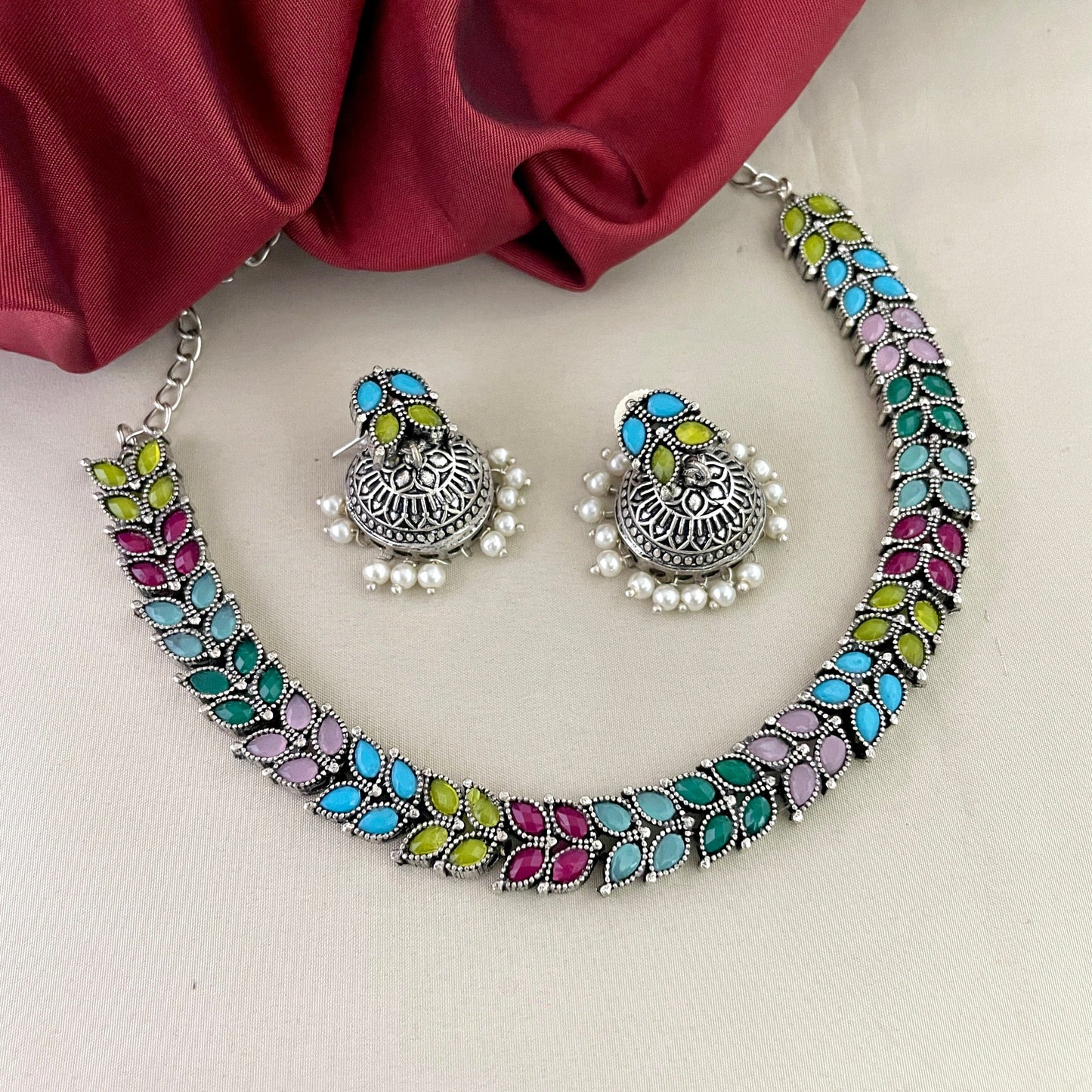 A colorful necklace and matching earrings set with intricate designs and pearl accents.