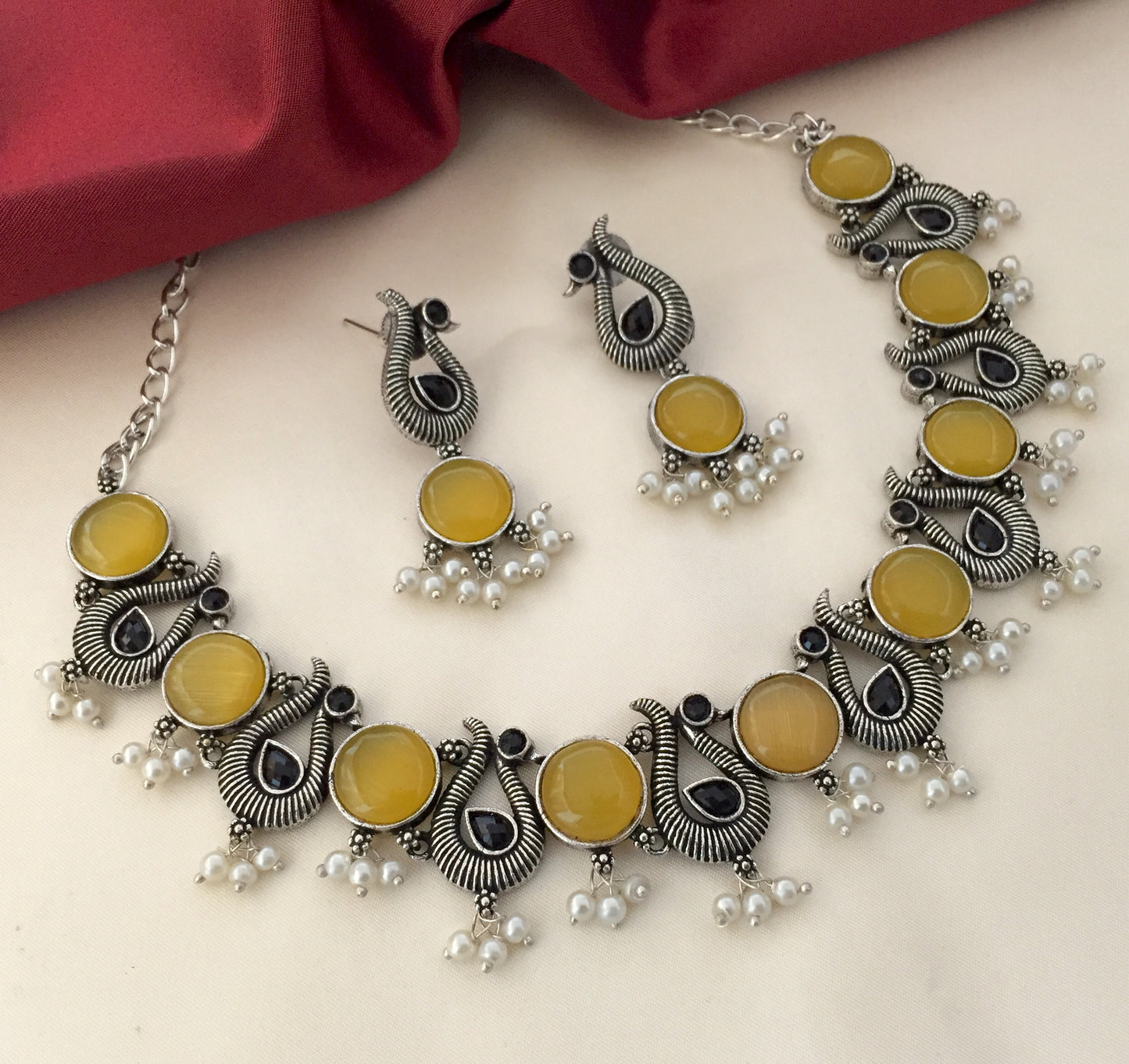 Silver necklace and earrings set with yellow stones and pearl accents.
