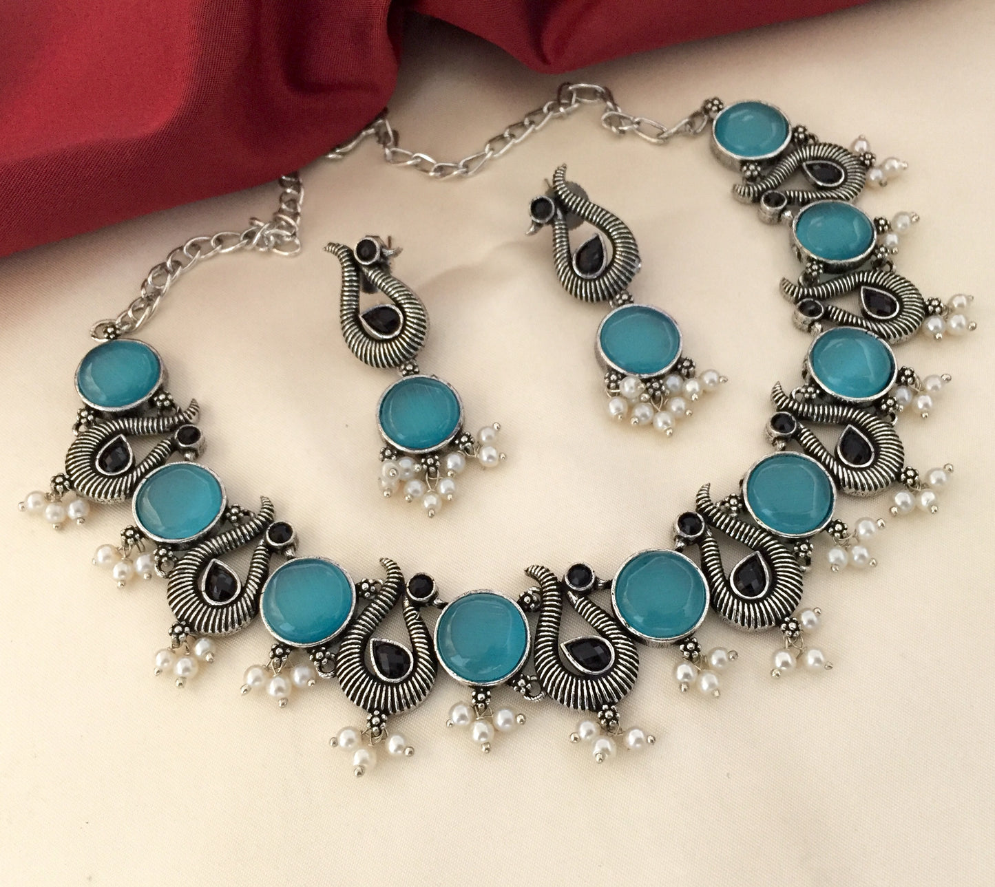 Silver necklace and earrings set with turquoise stones and pearl accents.