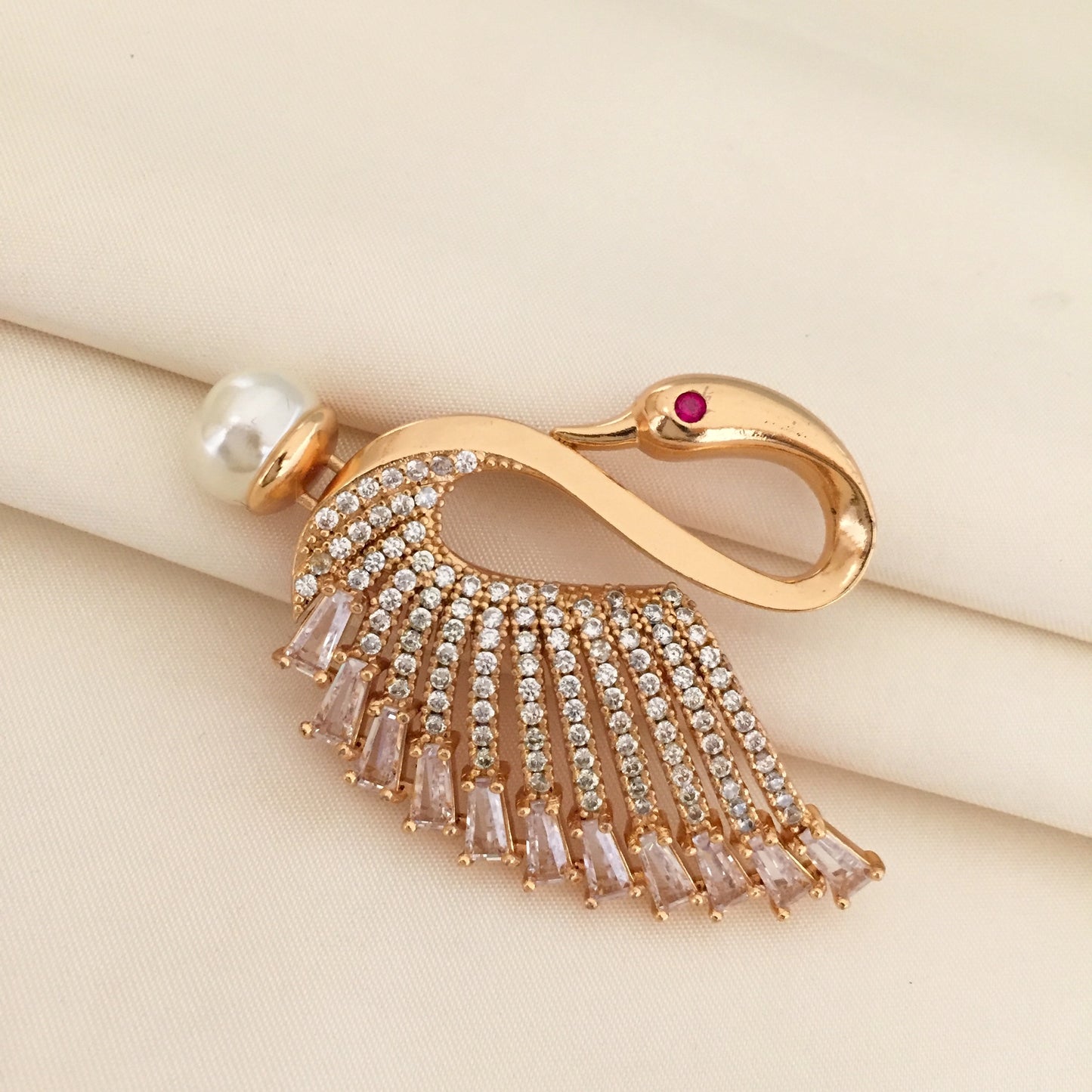 Gold swan-shaped brooch adorned with crystals and a pearl.