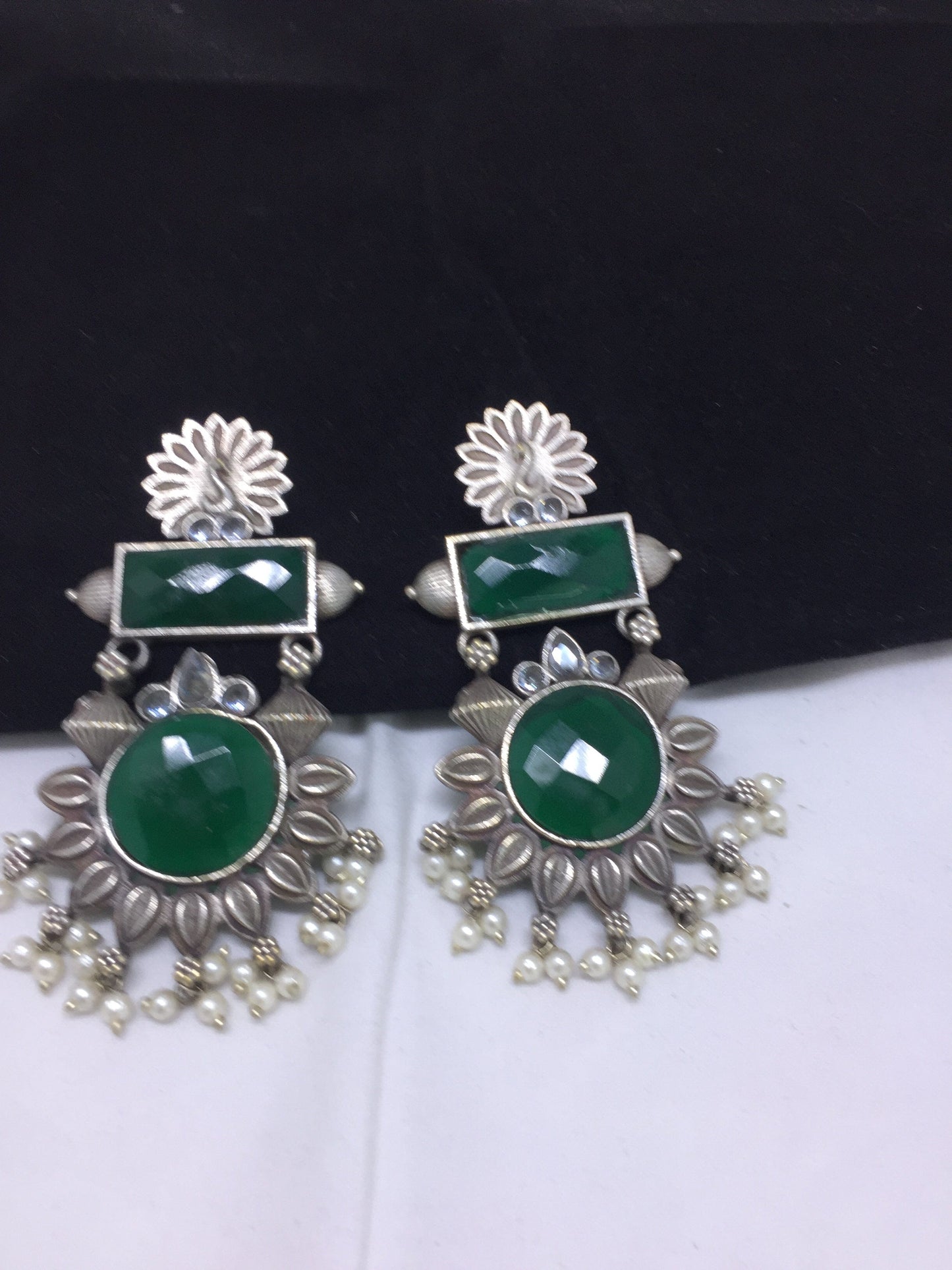 Silver and green gemstone earrings with floral design and pearl accents.