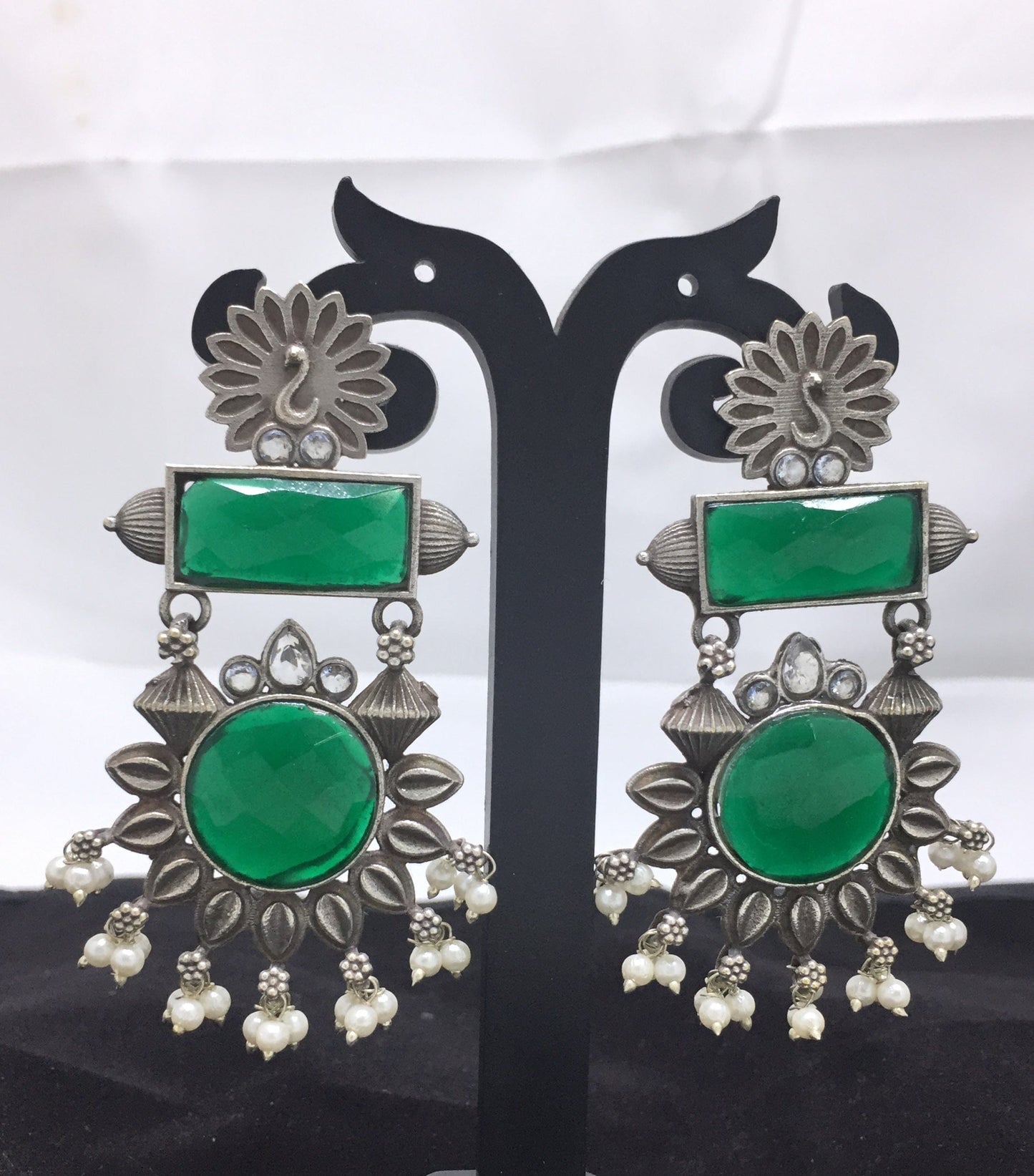 Silver and green gemstone earrings with intricate floral design and pearl accents.