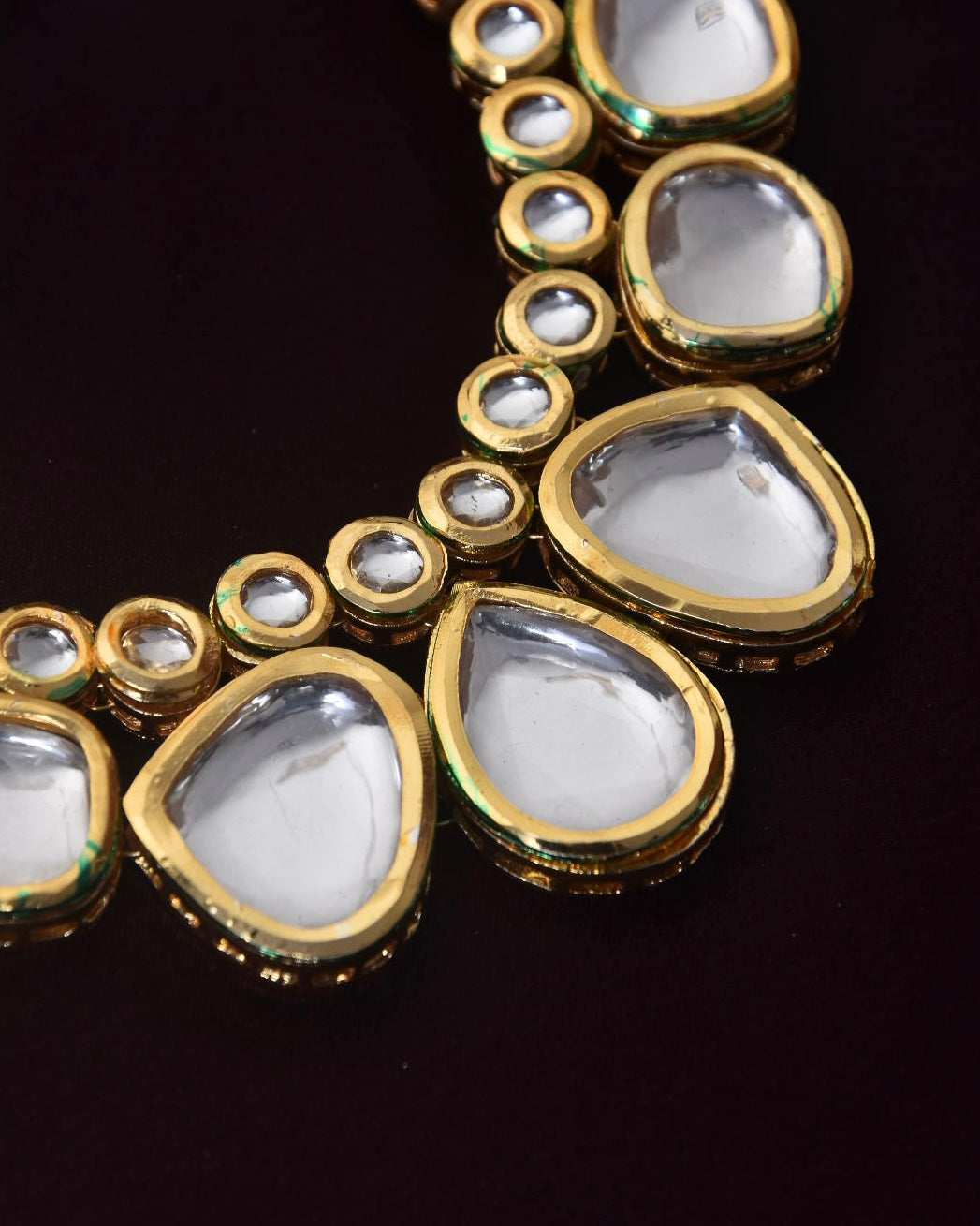 A close-up of a gold necklace with large teardrop-shaped and small round clear gemstones.