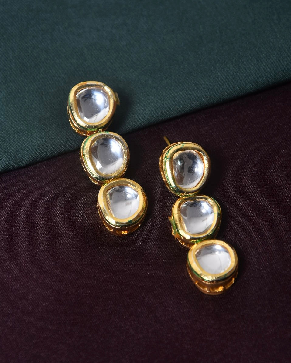 A pair of gold earrings with four clear gemstones each.