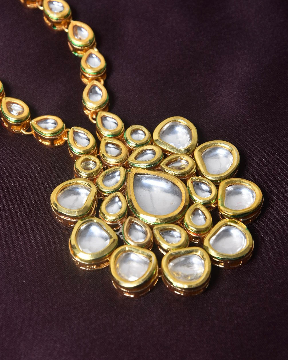 A gold necklace with a large pendant featuring multiple teardrop-shaped and oval white gemstones.