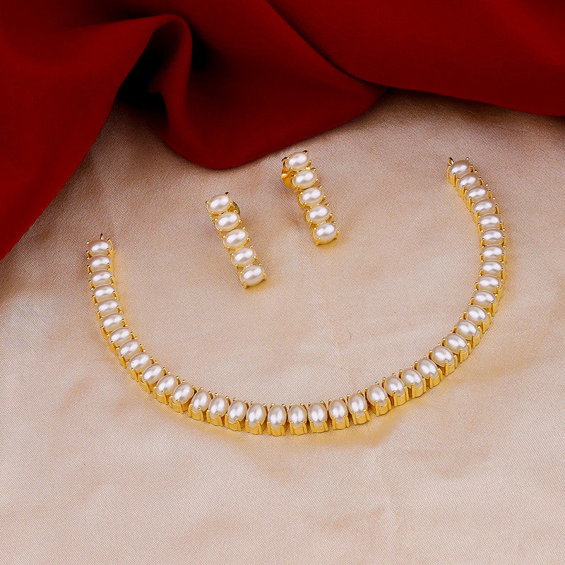 A gold and pearl jewelry set with a necklace and matching earrings displayed on a beige fabric with a red cloth in the background.