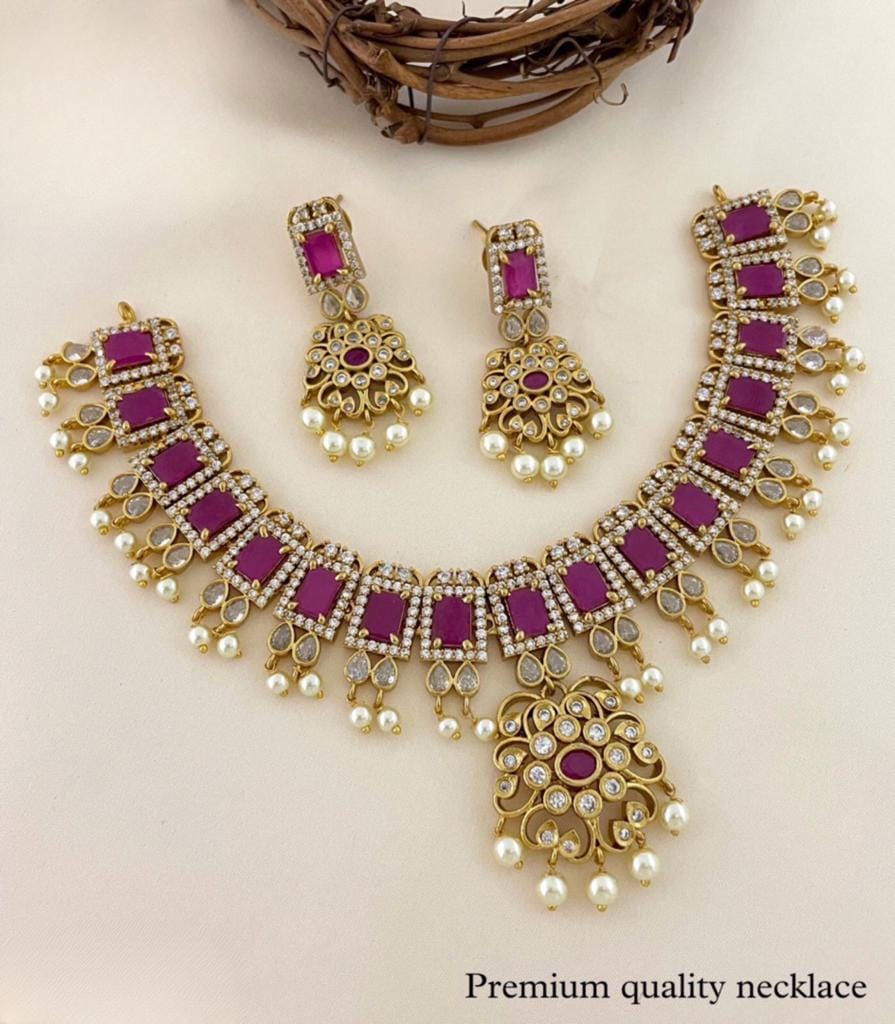 A gold necklace set with purple gemstones, white pearls, and matching earrings.