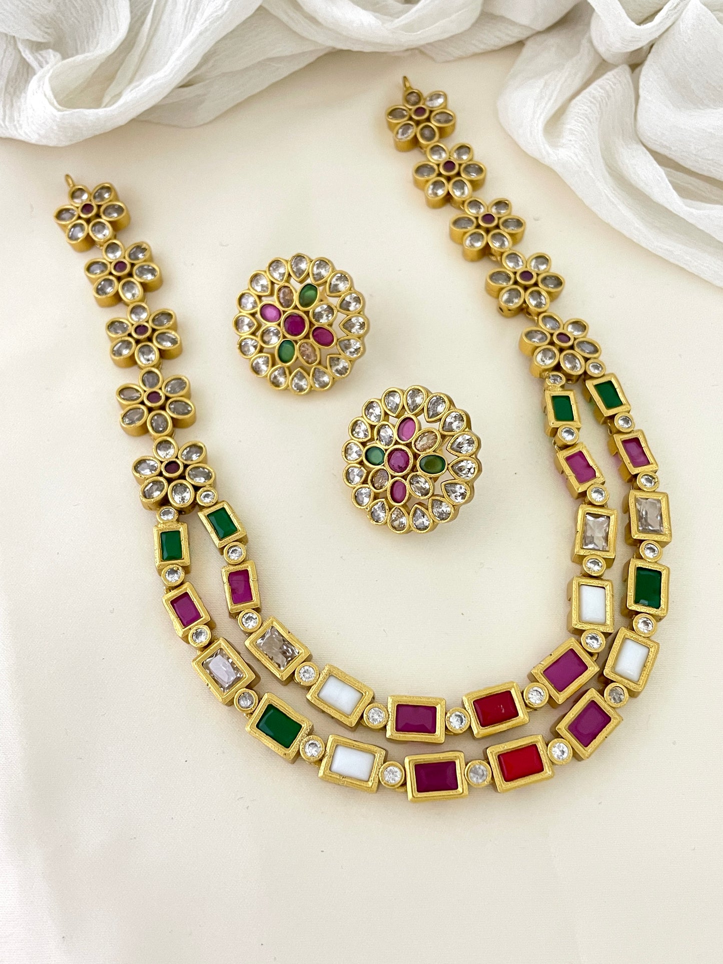 Gold necklace and earrings set with multicolored gemstones.