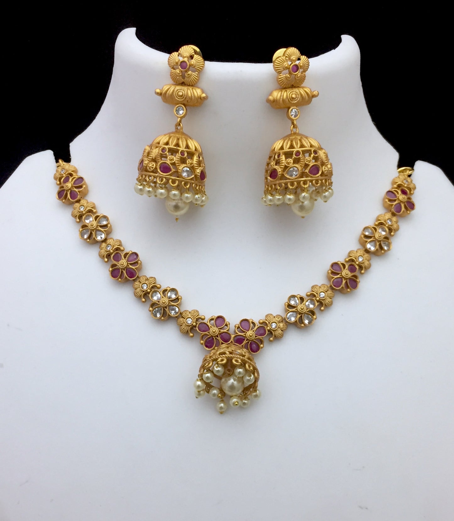 Gold necklace and earring set with floral designs, red gemstones, and pearl accents.