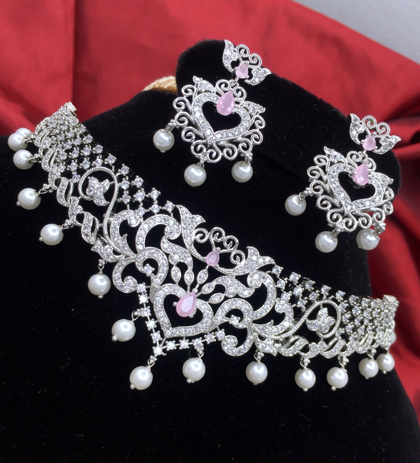 Silver-plated choker set with intricate designs, adorned with white pearls and pink stones, accompanied by matching earrings.
