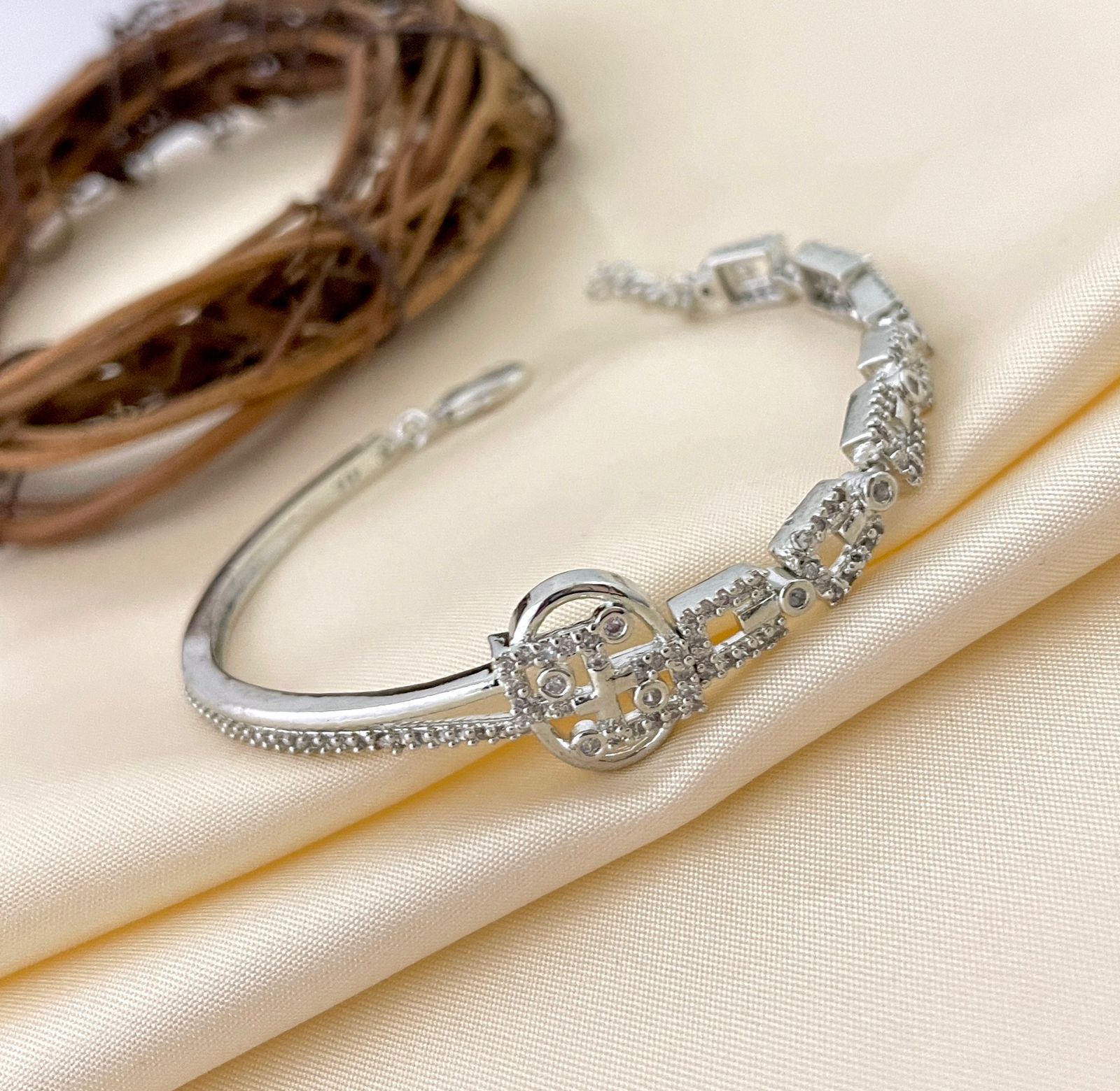 A silver bracelet with intricate American diamond detailing and a flexible design.