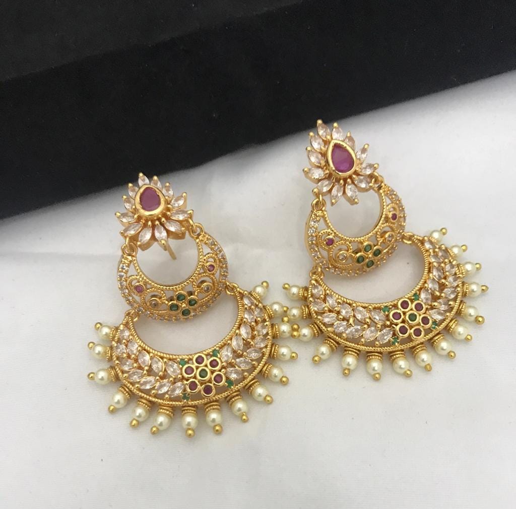 Gold chandbali earrings with intricate design, featuring red and green gemstones and pearl accents.
