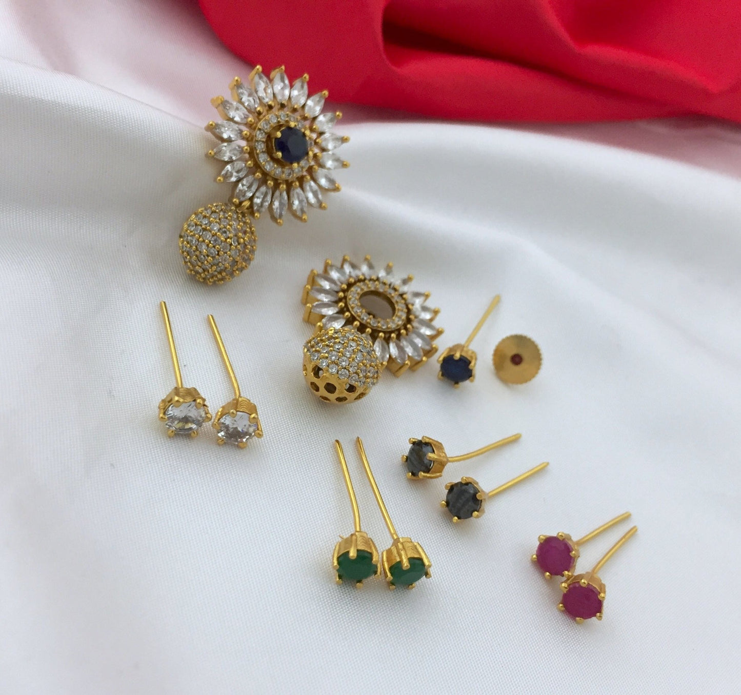A set of interchangeable American diamond earrings with various gemstone options including green, red, black, and clear stones.