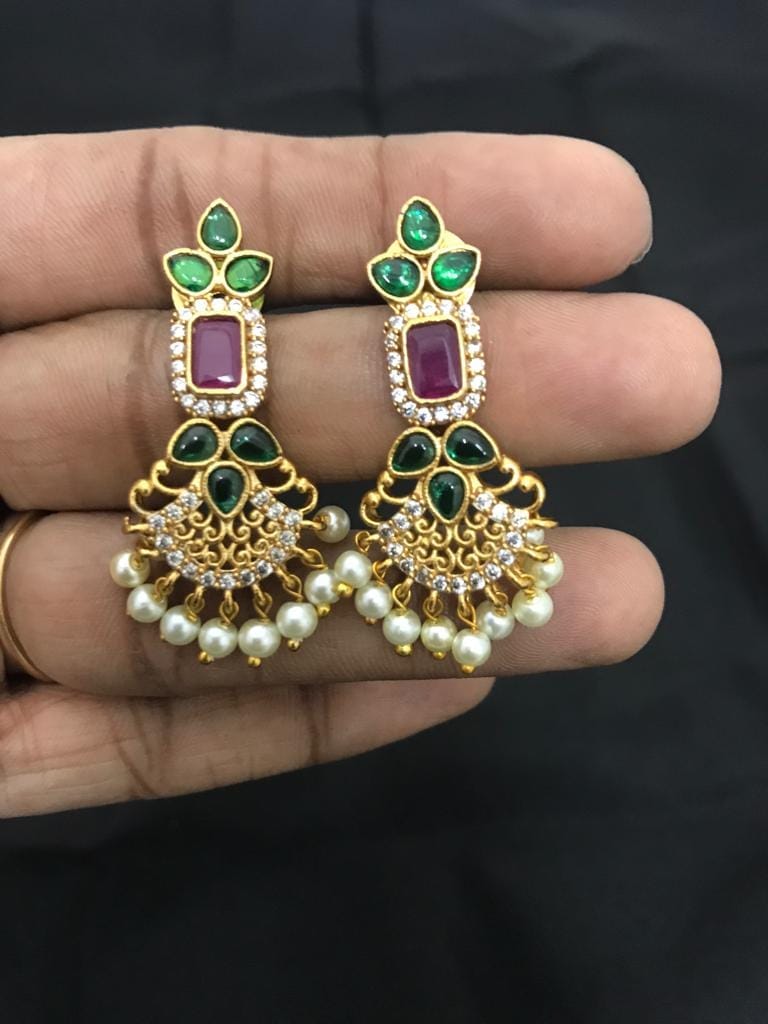 Gold earrings with green and purple gemstones, adorned with pearl dangles.