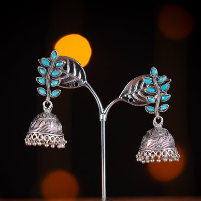 Silver jhumka earrings with turquoise leaf accents.