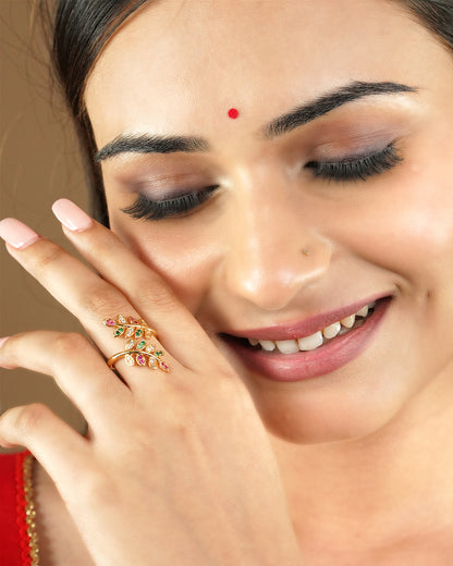 A woman wearing a gold ring with colorful gemstones shaped like leaves.
