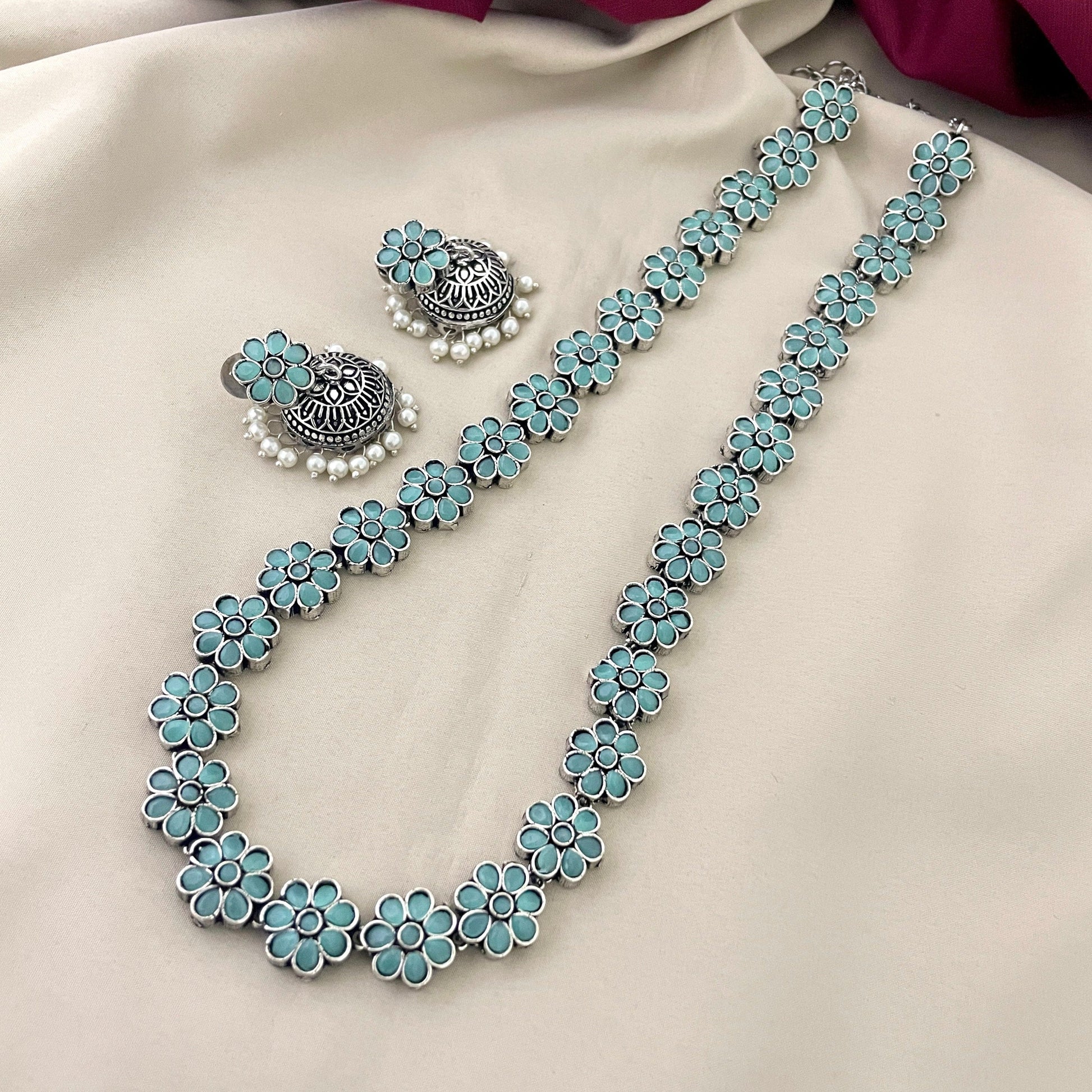 A jewelry set featuring a necklace and earrings with turquoise flower designs and silver accents.