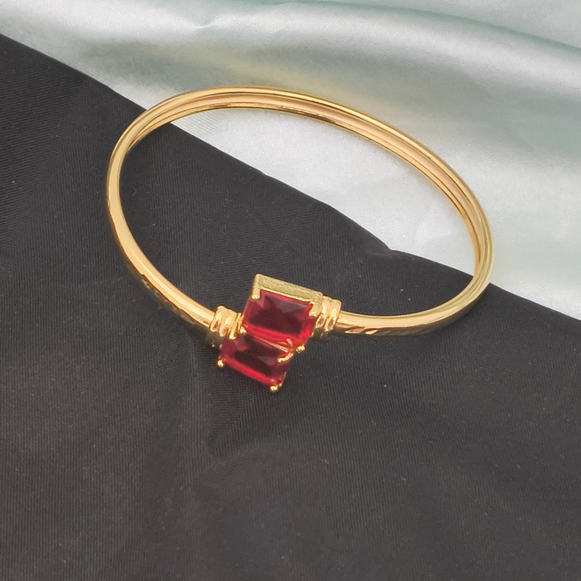 A gold bracelet featuring two rectangular red gemstones.