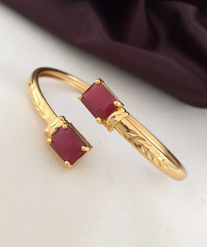 Gold bracelet with two rectangular red gemstones.