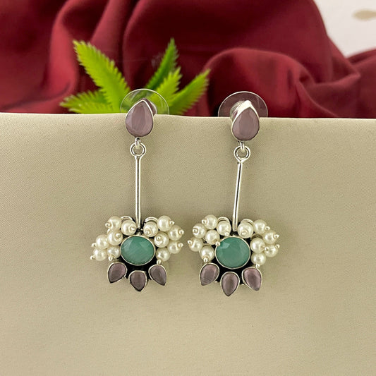 Silver dangle earrings with purple and green gemstones, pearl accents, and floral design.
