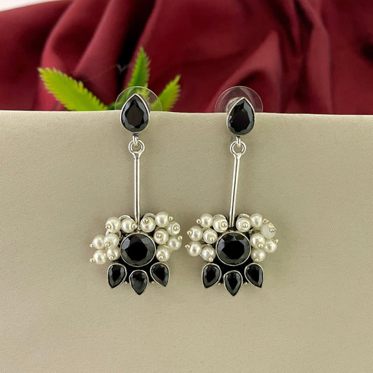 Silver earrings with black teardrop-shaped stones and small white pearls.