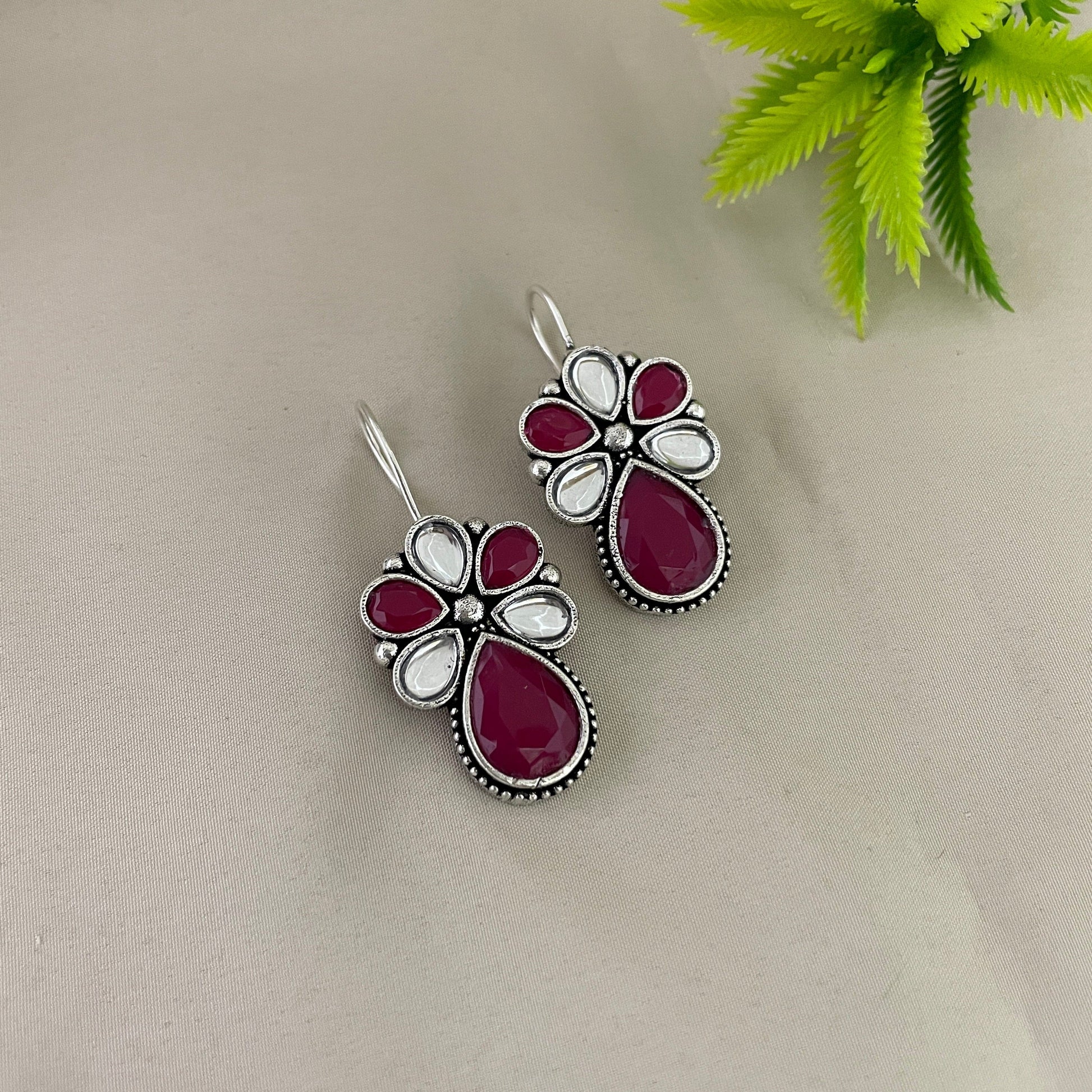 A pair of silver earrings with red and white gemstones.