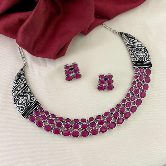 Silver necklace with intricate designs and multiple rows of pink stones, accompanied by matching pink stone earrings.