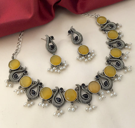 Silver necklace and earrings set with yellow stones and pearl accents.