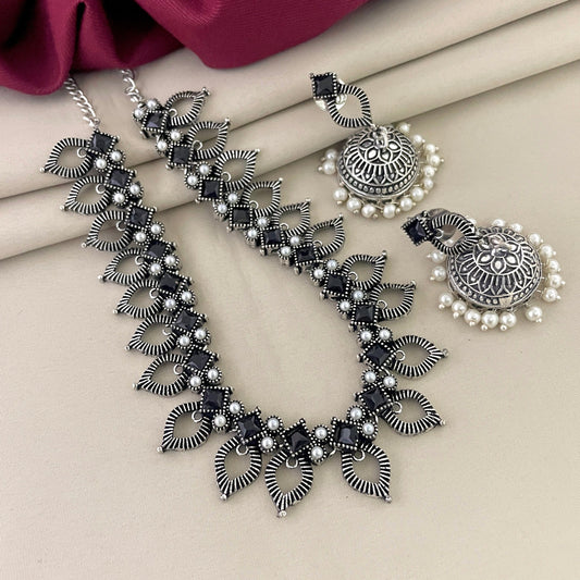 Silver necklace with intricate leaf design and matching earrings adorned with pearls.