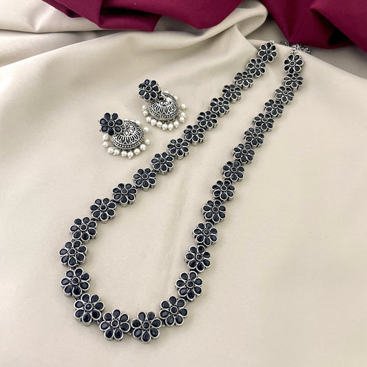 A silver floral necklace with matching earrings featuring intricate designs and pearl accents.