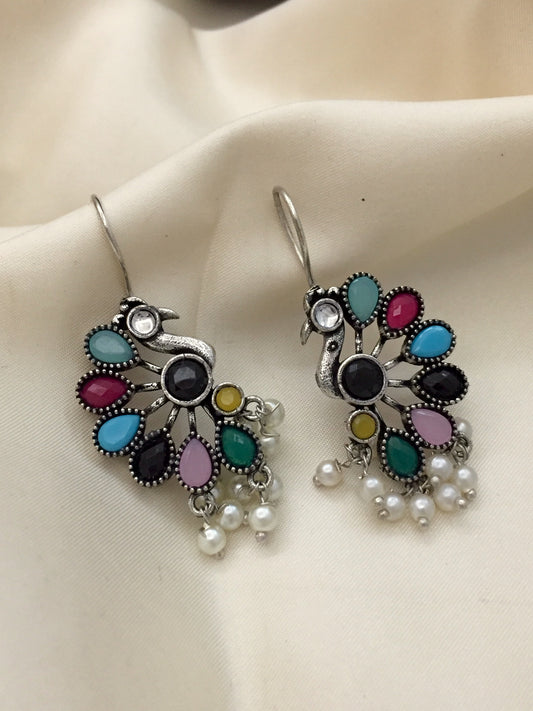 A pair of peacock-shaped earrings with colorful gemstones and dangling pearls.
