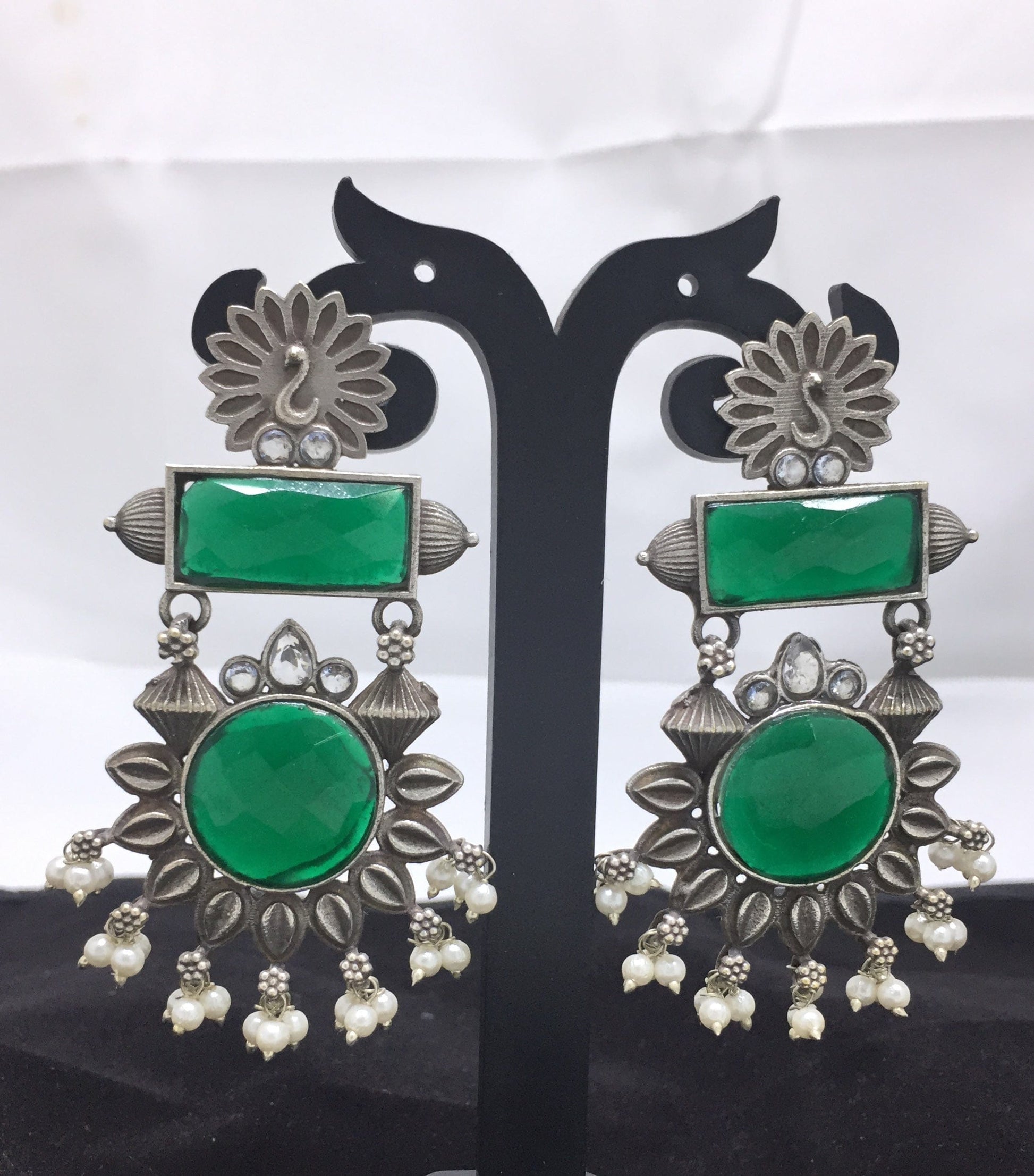 Silver and green gemstone earrings with intricate floral design and pearl accents.