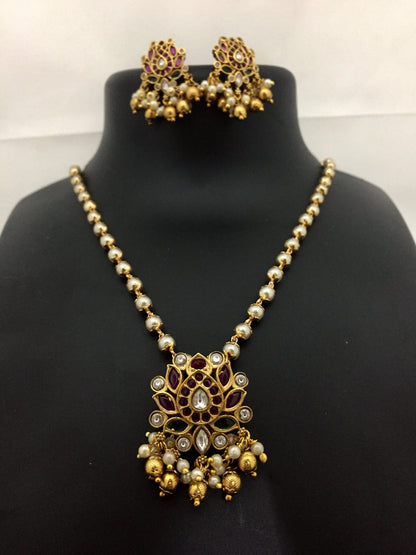 Gold and pearl necklace with matching earrings featuring intricate floral designs and dangling beads.