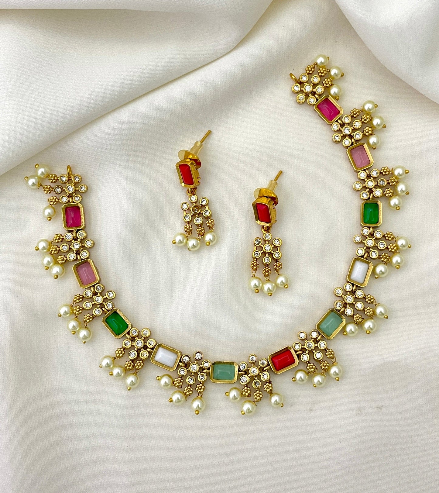 Gold necklace and earrings set with multicolored gemstones and pearl accents.