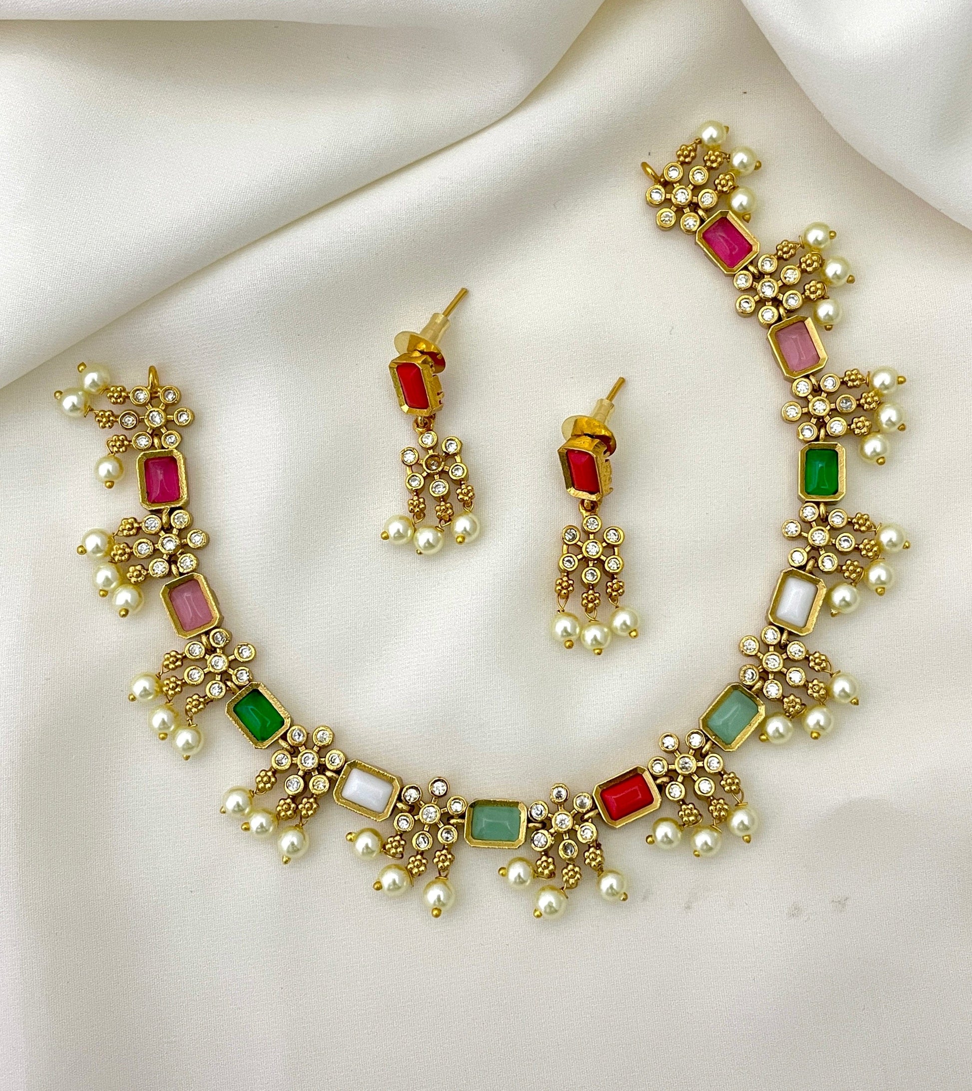 Gold necklace and earrings set with multicolored gemstones and pearl accents.