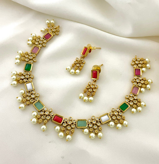 A gold necklace and matching earrings set adorned with multicolored gemstones, pearls, and small diamonds.
