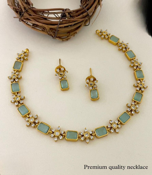 A gold necklace with rectangular green stones and matching earrings.