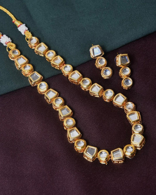 A gold necklace with square and rectangular gemstone settings, accompanied by matching earrings.