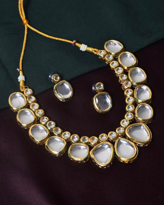 A gold necklace with large, clear gemstones and matching earrings.