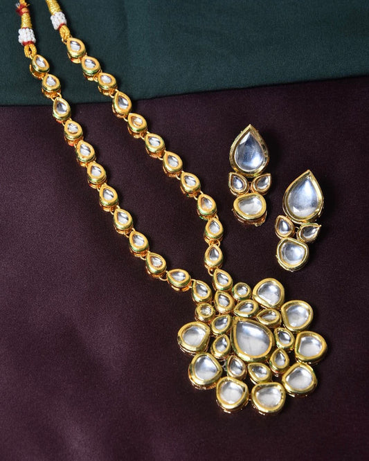 Gold necklace and earrings set with teardrop-shaped white stones.
