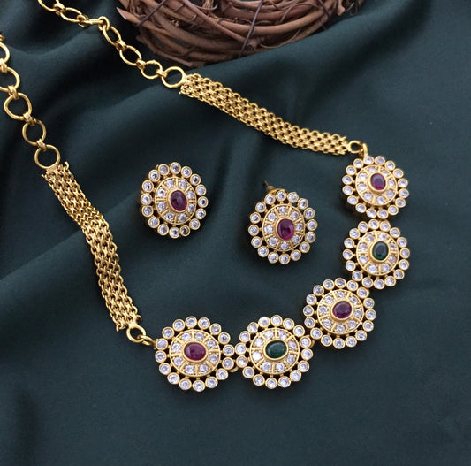A gold necklace with five circular pendants, each featuring a central gemstone surrounded by smaller clear stones, accompanied by matching circular earrings.