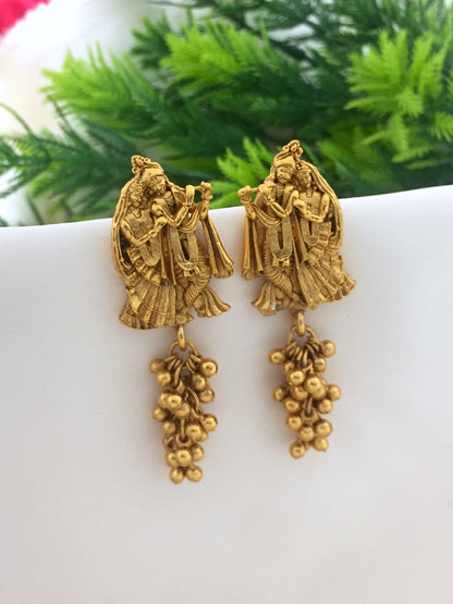 Gold-toned earrings featuring intricate designs of two figures and dangling bead clusters.