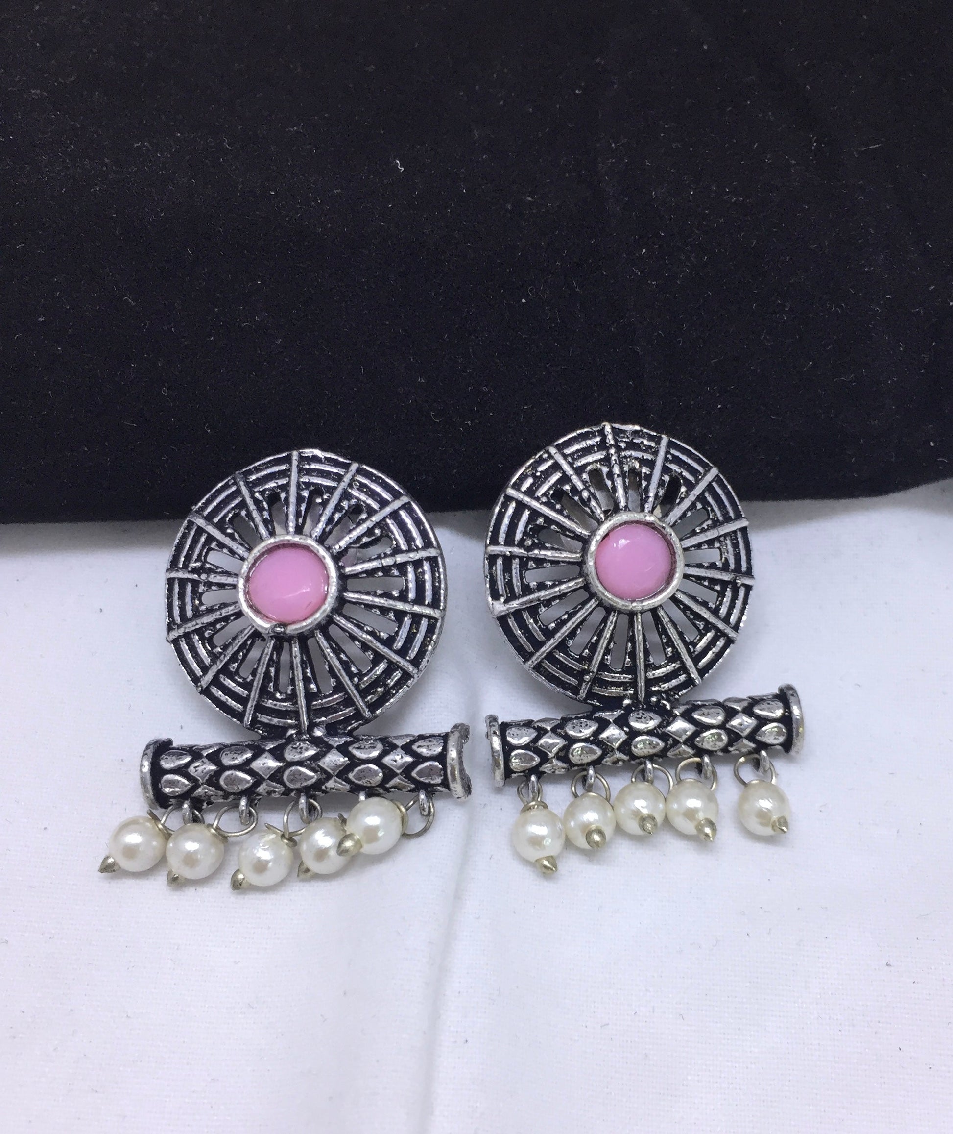 A pair of silver earrings with intricate designs, featuring a central pink stone and dangling white pearls.