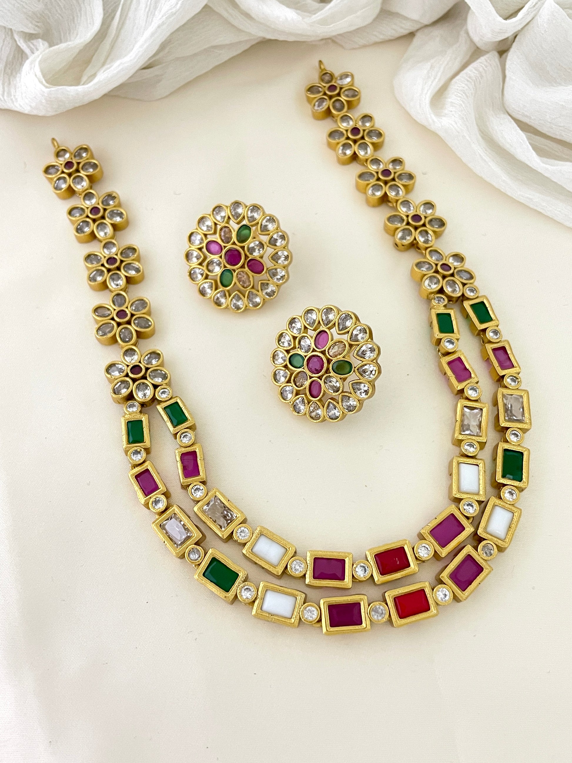 Gold necklace and earrings set with multicolored gemstones.